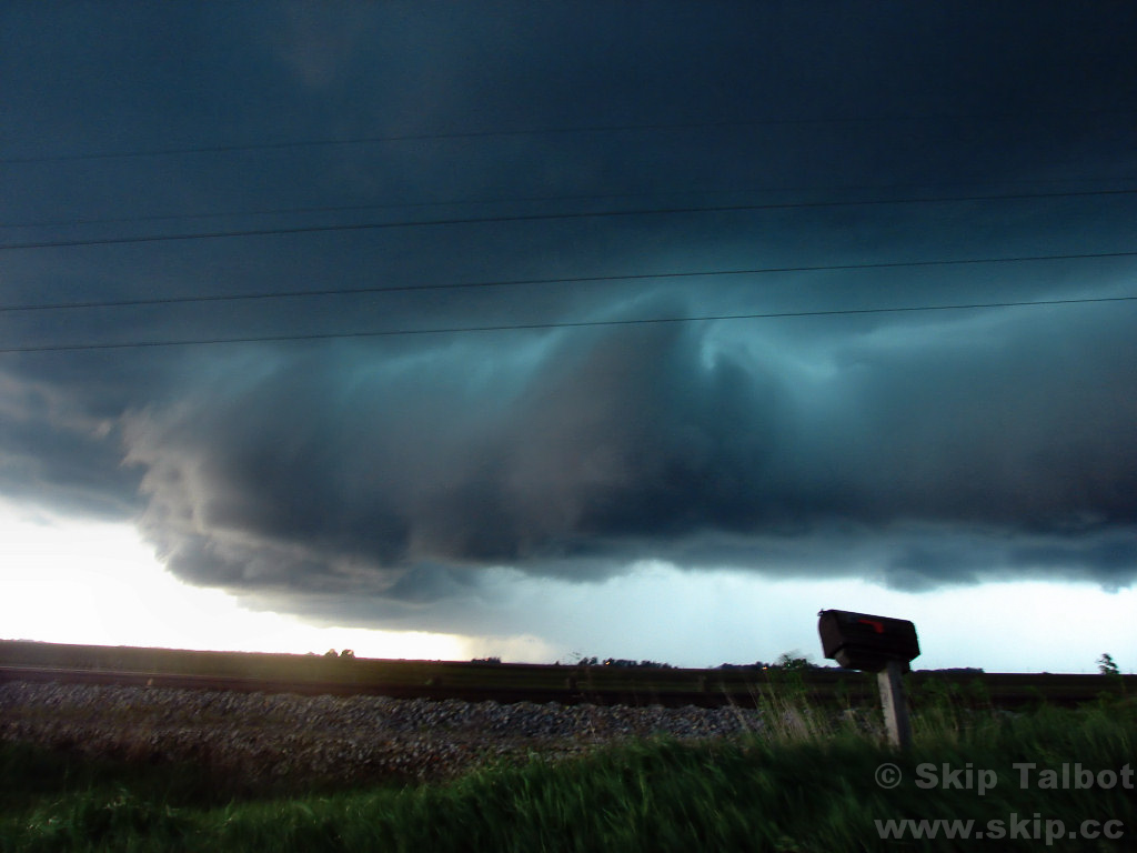 A dramatic shelf cloud and green core of a supercell thunderstorm
