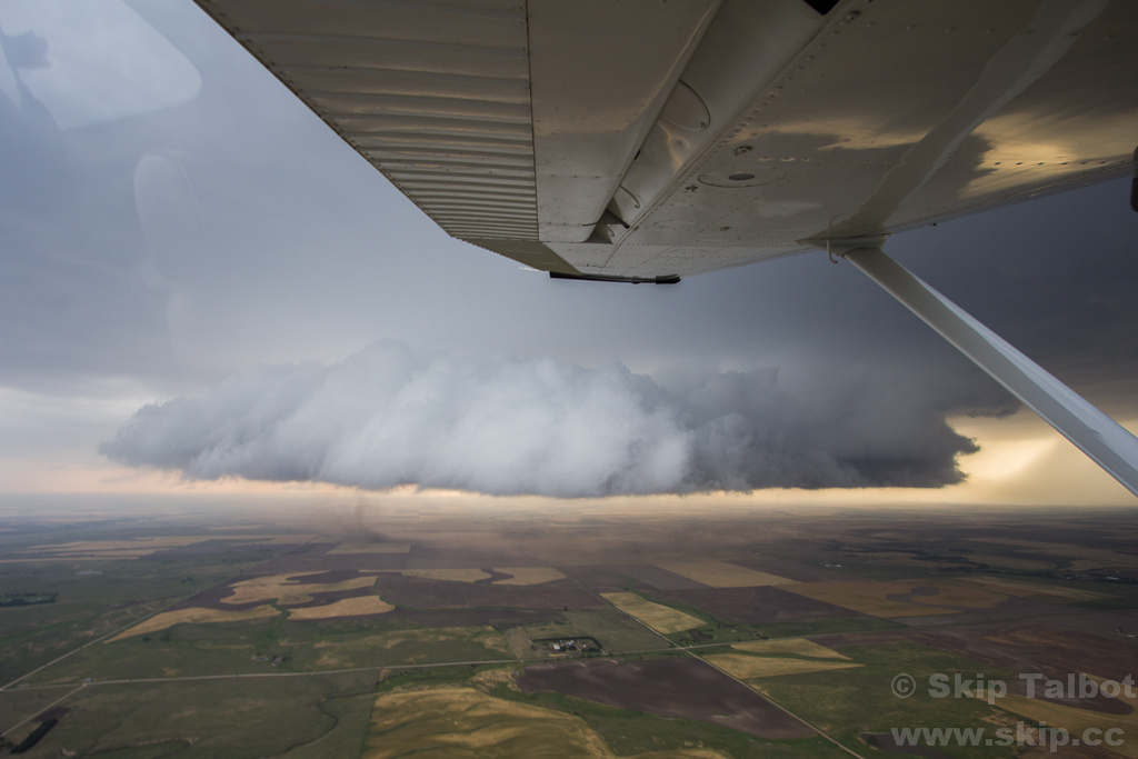 A large wall cloud drifts over the Kansas countryside with a dusty downdraft blast